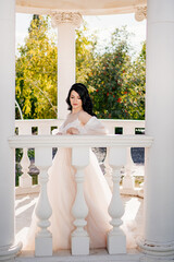 bride in wedding clothes at railing in gazebos or rotunda in the park.