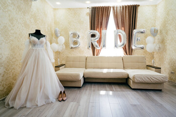 a room in the bride's house. wedding dress and shoes by the sofa with balloons.