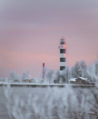 Lighthouse in colorful sunrise at seaside in frosty winter morning. Beautiful architecture.