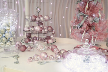 Beautiful christmas decor in silvery pink tones, christmas lights and toys on a concrete background