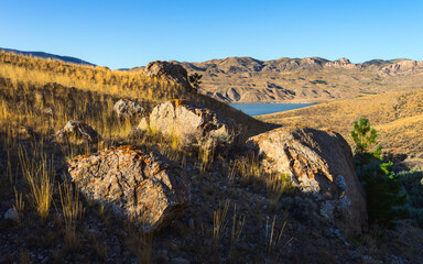 Arid landscape with boulders, grasses, and foothills of Rockies