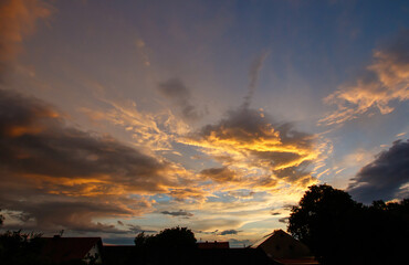 Mesmerizing view of a cloudy sky over the countryside with houses and dense trees at sunset