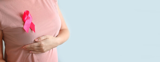 Breast Cancer Awareness and breast cancer self. A woman in a T-shirt with a pink ribbon doing...