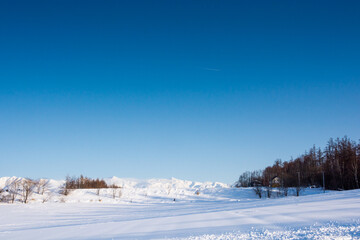 Fototapeta na wymiar 冬の晴れた日の雪原と山並み　十勝岳連峰 