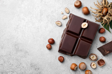 Delicious chocolate and hazelnuts on light table, flat lay. Space for text