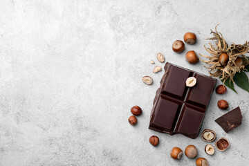 Delicious chocolate and hazelnuts on light table, flat lay. Space for text