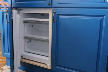 blue wooden kitchen interior fragment with fridge and human hand close up photo