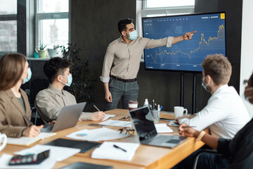 Colleagues having meeting in boardroom, businessman showing graph