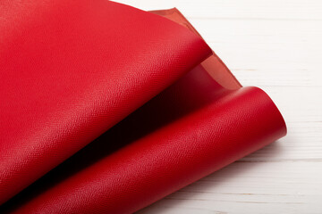 Red folded natural cow leather on the wooden table	
