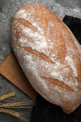 Loaf of tasty sodawater bread and wheat spikes on grey table, flat lay