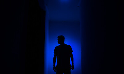 Silhouette of a guy in the dark.
Man in blue light.