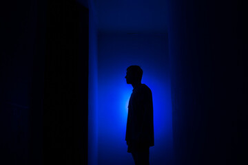 Silhouette of a guy in the dark.
Man in blue light.