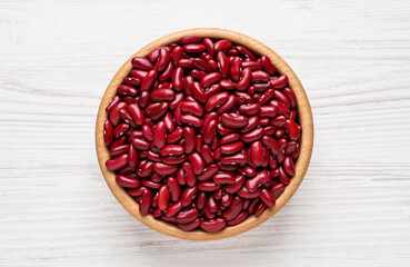 Raw red kidney beans in bowl on white wooden table, top view