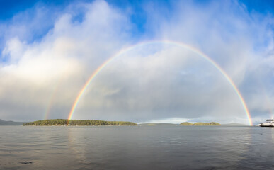 Double Rainbow in the cloudy sky over the pacific ocean and Gulf Islands in Background. West Coast in Vancouver Island, British Columbia, Canada. Panoramic Nature Background