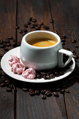 cup of espresso and pink meringues on wooden background, vertical