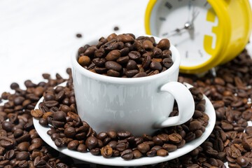 cup with coffee beans and an alarm clock, conceptual photography, closeup