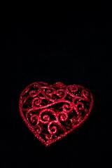 red decorative heart on black background, vertical closeup