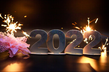 Numbers 2022 and sparklers of bengal lights on a black background.
