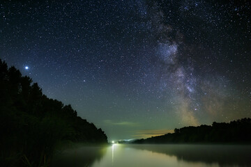 Fototapeta na wymiar Bright stars of the Milky Way in the night sky over the river with fog. Wonderful place for landscape.
