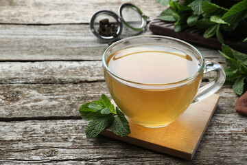 Cup of hot aromatic mint tea on wooden table. Space for text