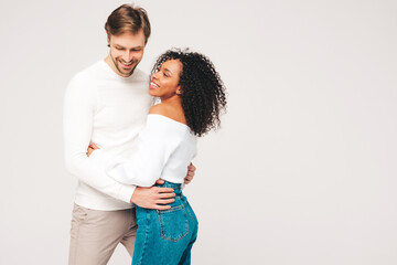 Smiling beautiful woman and her handsome boyfriend. Happy cheerful multiracial family having tender moments on grey background  in studio. Multiethnic models hugging. Embracing each other.Love concept