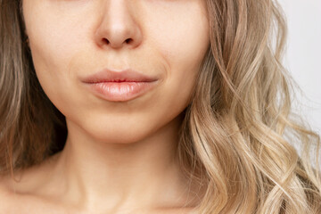Cropped shot of a young caucasian blonde woman with wavy hair. Close up of a lower part of the face...
