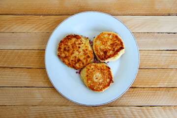 Homemade cheesecakes on a plate on the wooden background, top view