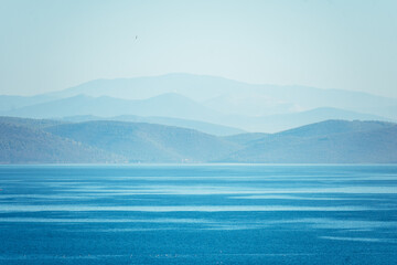 Natural blue background. Seascape with mountains on the horizon.