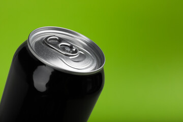 Black can of energy drink on green background, closeup. Space for text