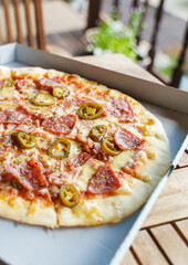 Crispy hot pizza with ham, pepperoni and jalapeno.