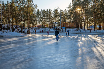 Townspeople skate on an outdoor ice rink on a sunny winter day