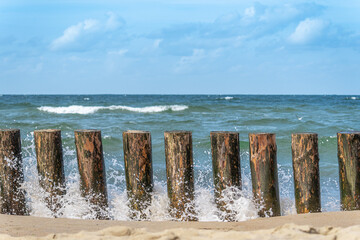 Restless sea waves are running over the wooden breakwater.