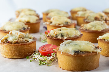 Blurred image of mushroom cheese tartlets on a plate with micro greens and cherry tomatoes.