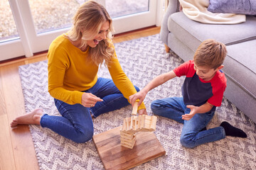 Mother And Son At Home Playing Game Stacking Wooden Blocks Which Collapse