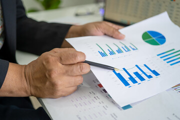 Asian accountant working and analyzing financial reports project accounting with chart graph and calculator in modern office, finance and business concept.