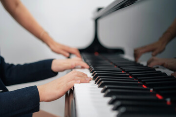 Fototapeta premium Selective focus on the kid finger playing grand piano. Teacher or instructor teach a boy on the class play melody. Close up hand of child. Music with piano. Education and learning concept..