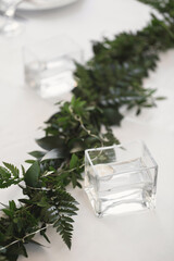 Decor of candles and green flowers on the wedding table in the restaurant.
