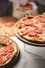 There are many different freshly prepared pizzas on the buffet table.