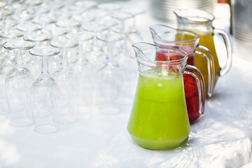 Glasses and glass decanters with orange and grape juice on the table.
