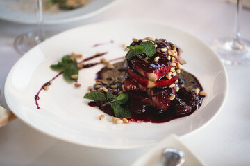 Foie gras with sauce, herbs and nuts on a plate.