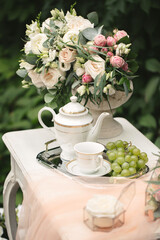 Romantic photo zone for the bride's wedding day gatherings. Table, flowers and rose petals in the forest.