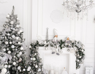 christmas tree with white decorations and white fireplace. Copception of decor in white silver color, light colors for Christmas and New Year.