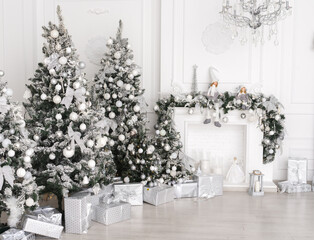 christmas tree with white decorations and white fireplace. Copception of decor in white silver color, light colors for Christmas and New Year.