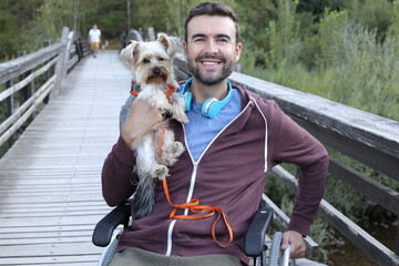Handsome man on a wheelchair with his cute Yorkshire terrier - obrazy, fototapety, plakaty