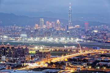 Naklejka premium Aerial panorama of busy Taipei City, Keelung River, Dazhi Bridge, Songshan Airport & Taipei 101 in XinYi District at dusk ~ A romantic night in Taipei downtown with beautiful skyline in background 
