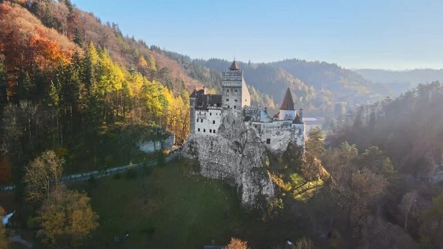 Aerial drone view of The Bran Castle in Romania. Medieval castle in Carpathians, yellowed trees, tourists