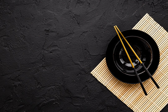 Asian tabble place setting with golden chopsticks on black bowl