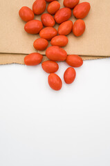 ripe fresh bio organic datterini tomatoes and brown paper bag on a white background
