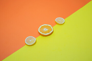 two slices of lemon and one slice of orange on an orange and yellow background
