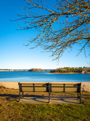 Fototapeta na wymiar Seascape with two benches on the hill looking over the island in Buzzard Bay. Tranquil seascape over the Onset Bay and Beach in Onset, Massachusetts in winter.